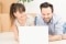 The picture shows a couple in front of a laptop.