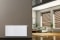 Bộ tản nhiệt đa năng Vitoset, phía sau là phòng khách có cửa sổ được kéo kín rèm, ghế sofa, cây cảnh và cây cọ.
