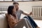 A happy couple are sitting in front of a heating system and holding a smartphone.