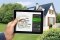 Tablet mit Modernisierungsrechner, im Hintergrund: Einfamilienhaus